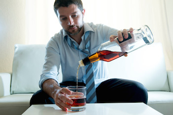 Businessman wearing blue shirt drunk at desk on white background